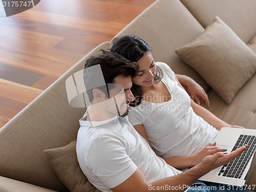 Image of relaxed young couple working on laptop computer at home