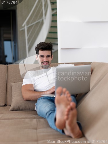 Image of Man Relaxing On Sofa With Laptop