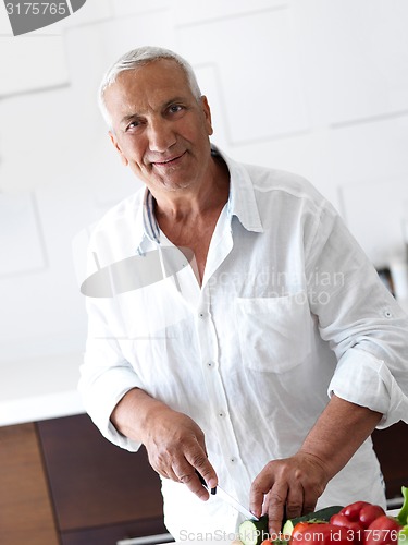 Image of man cooking at home preparing salad in kitchen