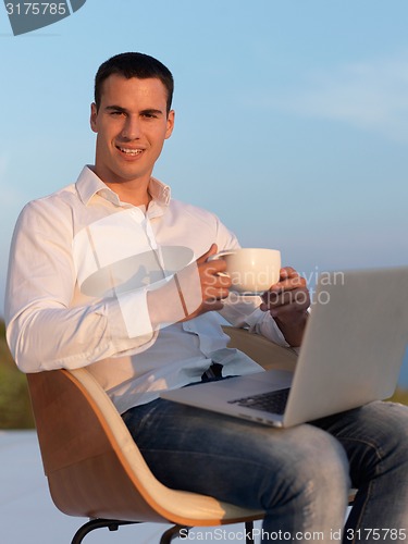 Image of relaxed young man at home on balcony