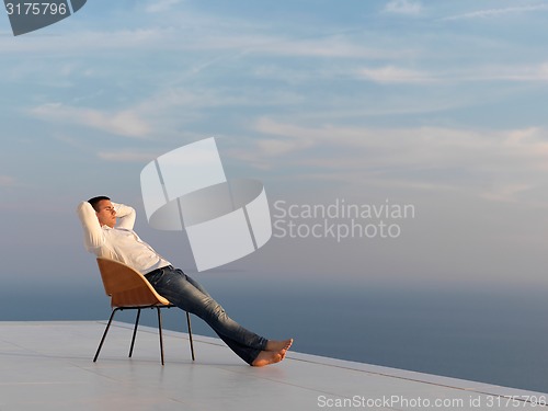 Image of relaxed young man at home on balcony