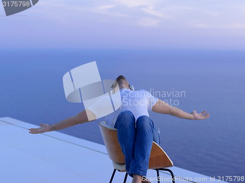 Image of relaxed young man at home on balcony