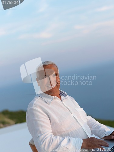 Image of relaxed senior man on balcony