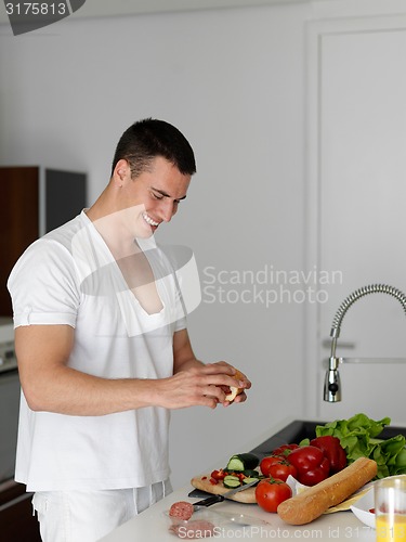 Image of man cooking at home preparing salad in kitchen