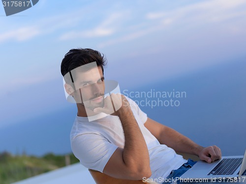Image of relaxed young man at home on balcony