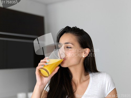 Image of woman drinking juice in her kitchen