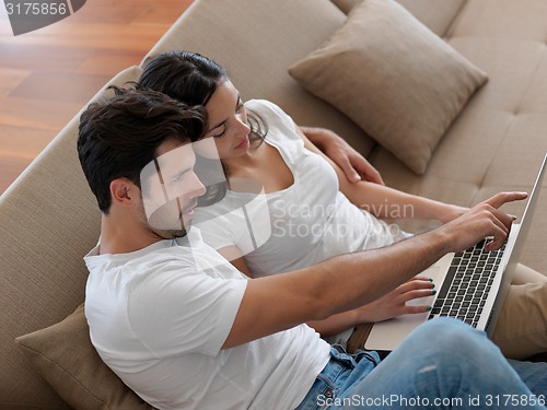 Image of relaxed young couple working on laptop computer at home