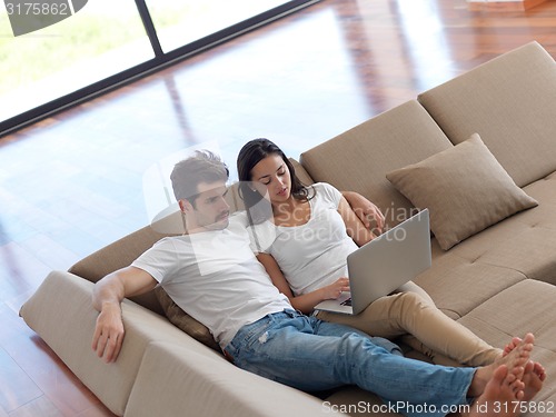 Image of relaxed young couple working on laptop computer at home