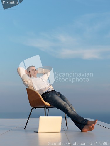 Image of relaxed young man at home on balcony