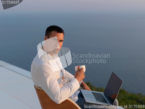 Image of relaxed young man at home on balcony
