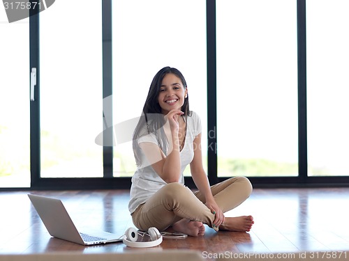 Image of relaxed young woman at home working on laptop computer