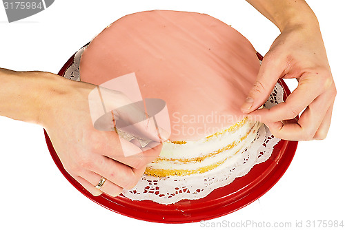 Image of Professional cake baker making the final touch when covering a c