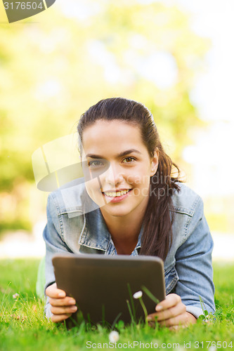 Image of smiling young girl tablet pc lying on grass