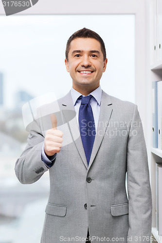 Image of happy businessman showing thumbs up in office