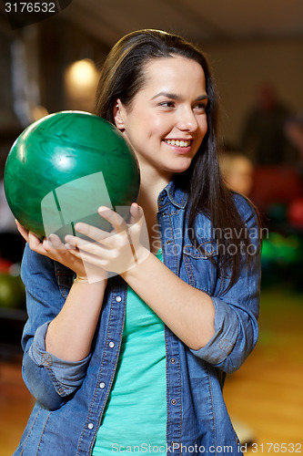 Image of happy young woman holding ball in bowling club