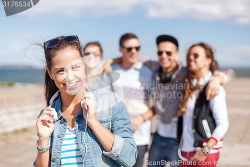 Image of teenage girl with headphones and friends outside