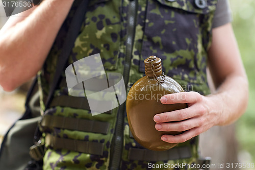 Image of close up of soldier with gun and flask in forest