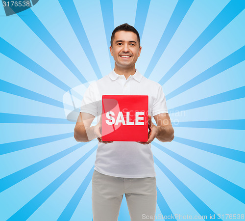 Image of smiling man with red sale sigh