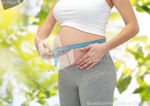 Image of close up of pregnant woman measuring her tummy