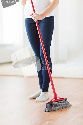 Image of close up of woman legs with broom sweeping floor