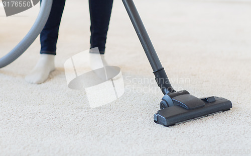 Image of close up of woman legs with vacuum cleaner at home