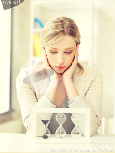 Image of pensive businesswoman with sand glass