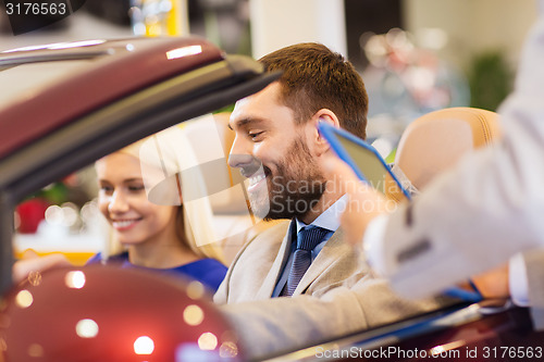 Image of happy couple with car dealer in auto show or salon