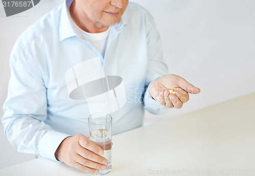 Image of close up of old man with pills and water glass