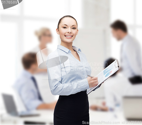 Image of young smiling businesswoman with clipboard and pen