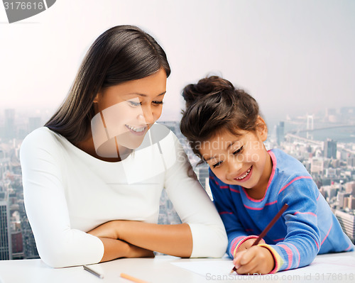 Image of happy mother and daughter drawing with pencils