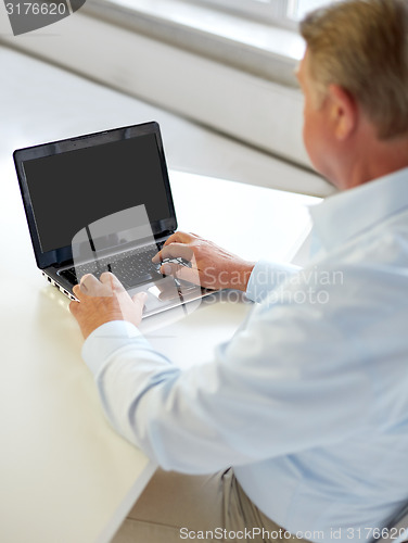 Image of close up of senior man with laptop typing
