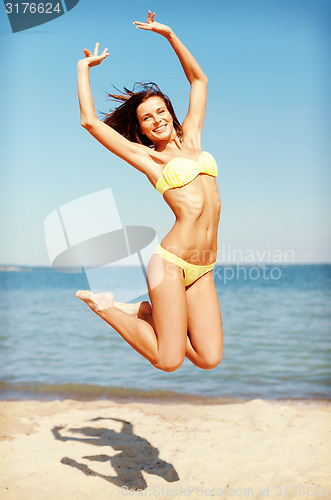 Image of woman in bikini jumping on the beach