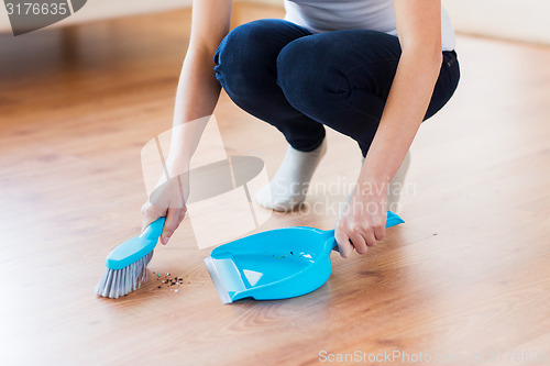 Image of close up of woman with brush and dustpan sweeping