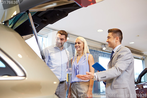 Image of happy couple with car dealer in auto show or salon