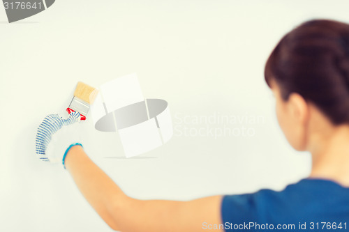 Image of woman with paintbrush colouring the wall