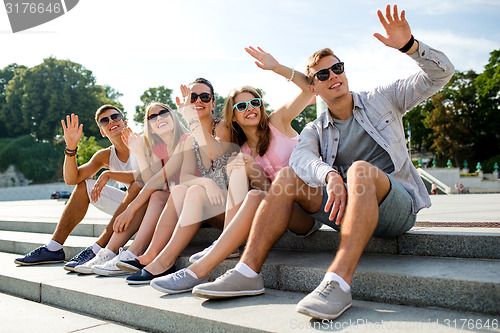 Image of group of smiling friends sitting on city street
