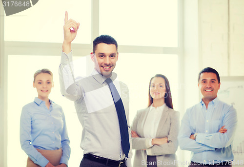 Image of smiling businessman in office with team on back