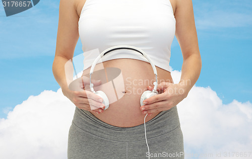 Image of close up of pregnant woman and headphones on tummy