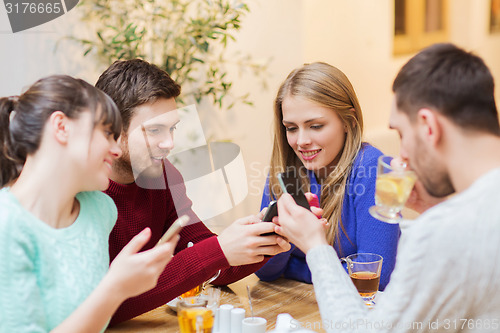 Image of group of friends with smartphones meeting at cafe
