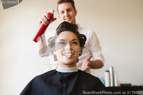 Image of happy woman with stylist making hairdo at salon