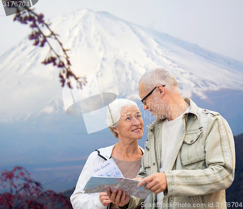 Image of happy senior couple with travel map over mountains