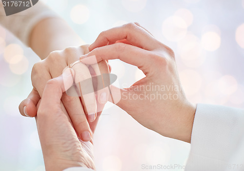 Image of close up of lesbian couple hands with wedding ring