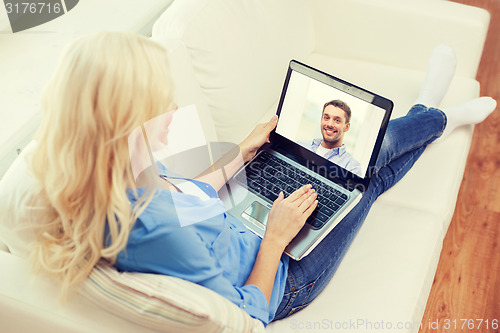 Image of smiling woman with laptop computer at home