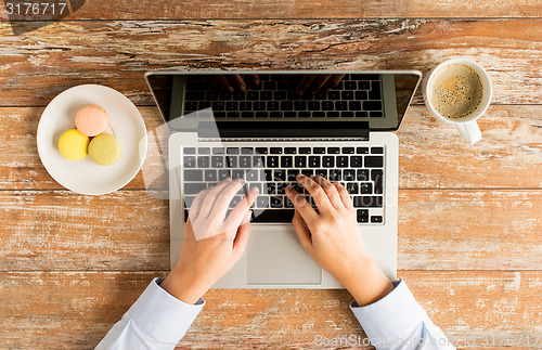 Image of close up of female hands with laptop and coffee