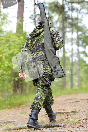 Image of young soldier or hunter with gun in forest