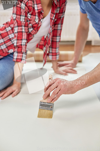 Image of close up of couple smearing wallpaper with glue