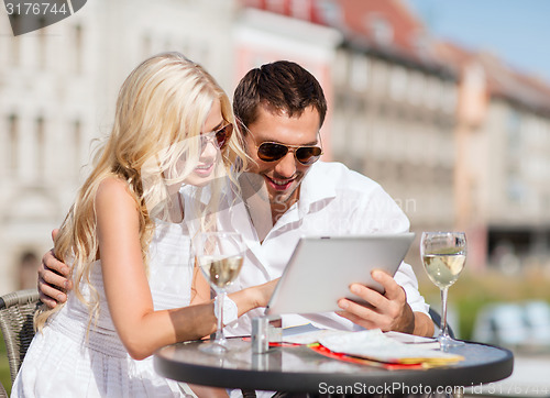 Image of couple looking at tablet pc in cafe