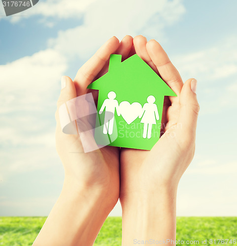 Image of hands holding green house with family