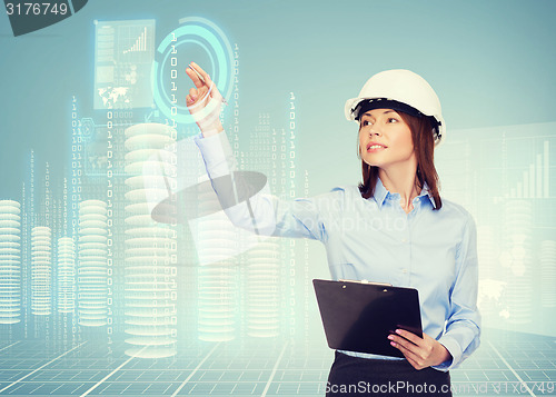 Image of smiling businesswoman in helmet with clipboard