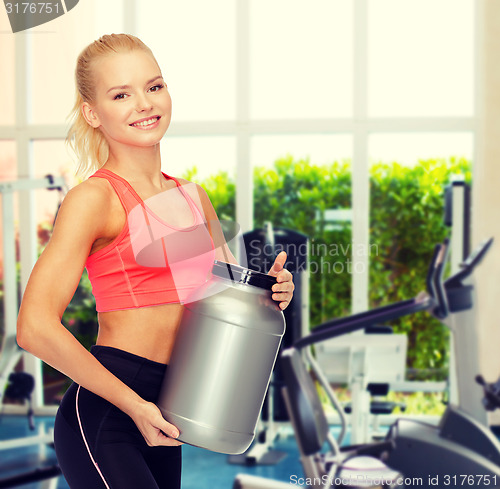 Image of smiling sporty woman with jar of protein